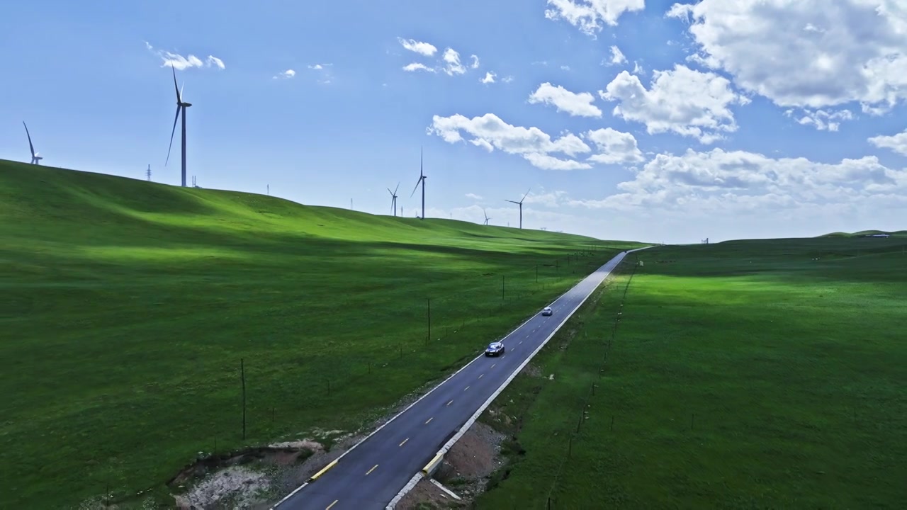 新能源电动车行驶在祁连山草原上的风力发电场视频下载