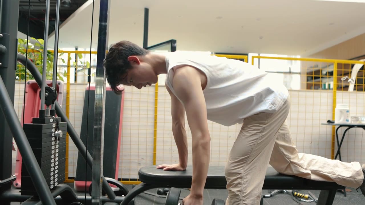 一个亚洲男人在健身房使用哑铃锻炼视频素材