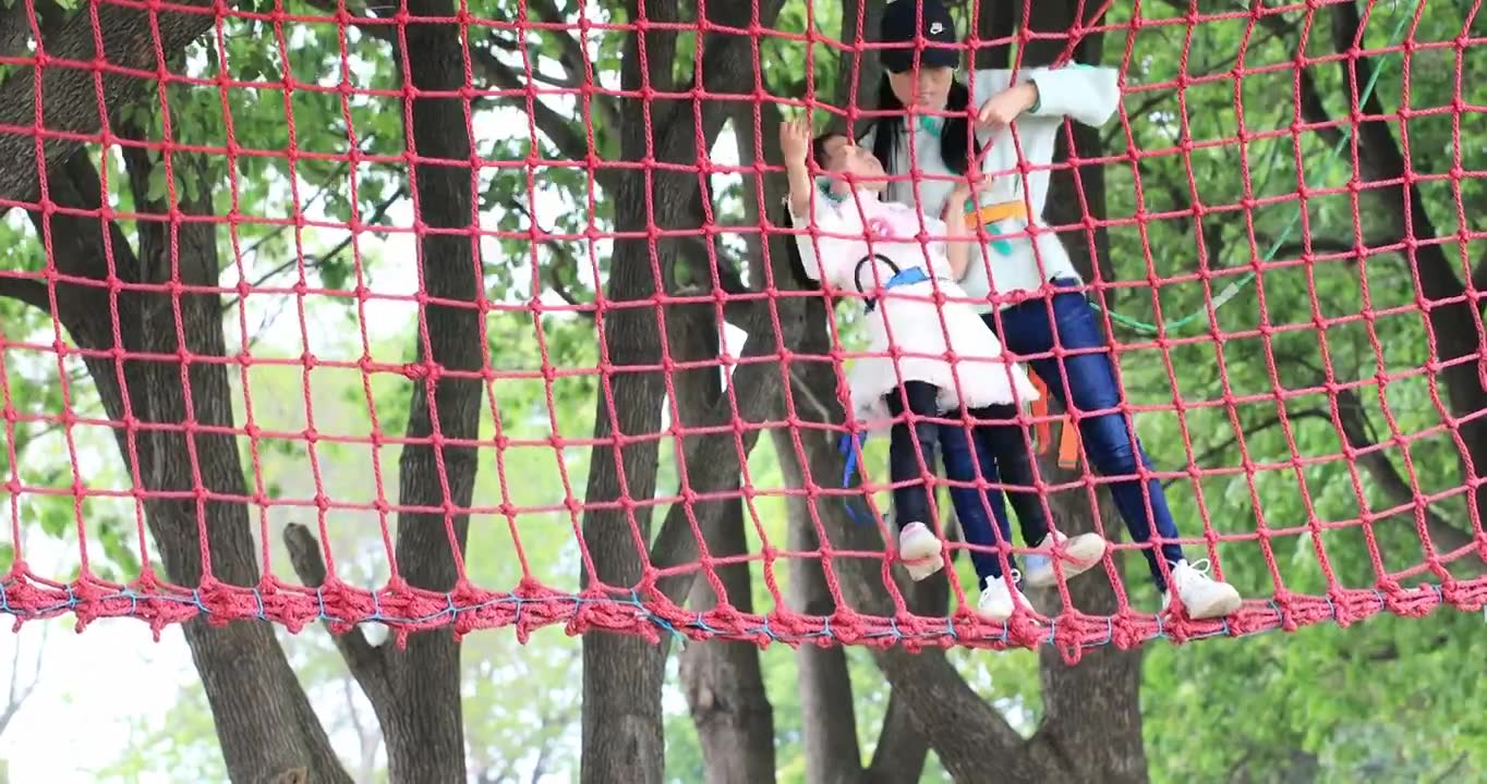 勇敢的小女孩系着安全带与妈妈一起 在高空行走爬绳网挑战自我视频下载
