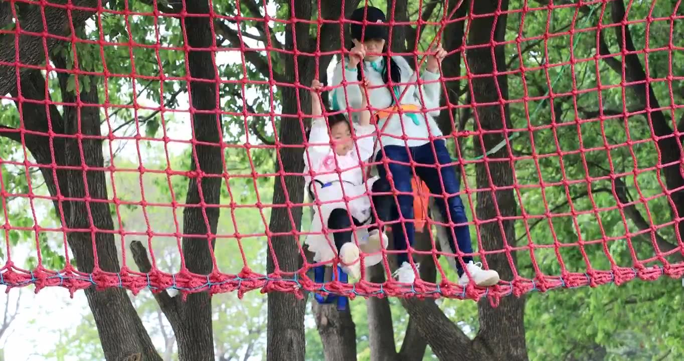勇敢的小女孩系着安全带与妈妈一起 在高空行走爬绳网挑战自我视频下载