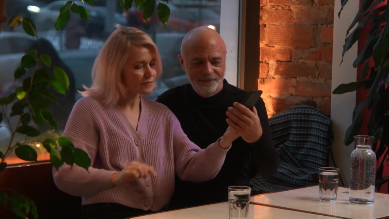 优雅的高级女性在与丈夫共进晚餐时对着智能手机拍照视频下载
