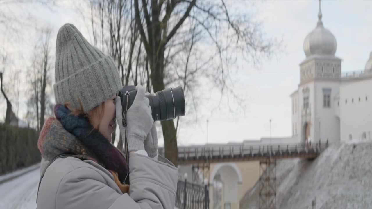 一位穿着保暖衣服的妇女正在拍摄美丽的冬季古城视频下载