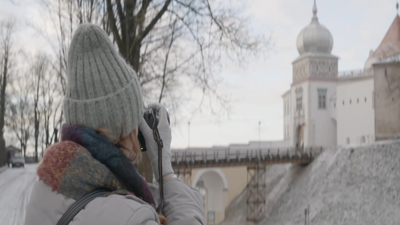 一位穿着保暖衣服的妇女正在拍摄美丽的冬季古城视频下载