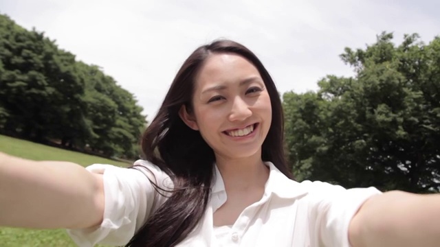 一名迷人的年轻日本女子在城市公园自拍视频素材