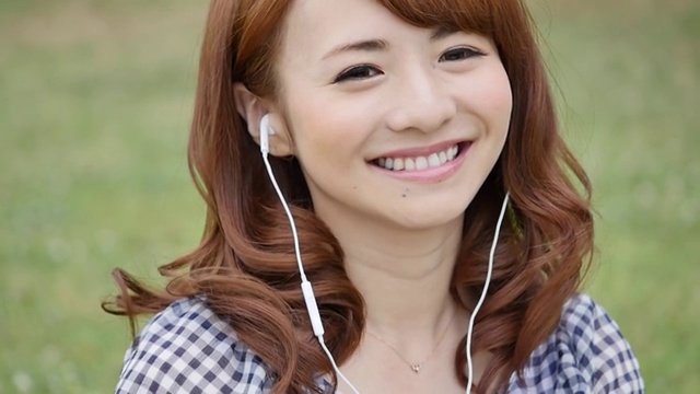 年轻迷人的日本女子在城市公园听音乐视频素材