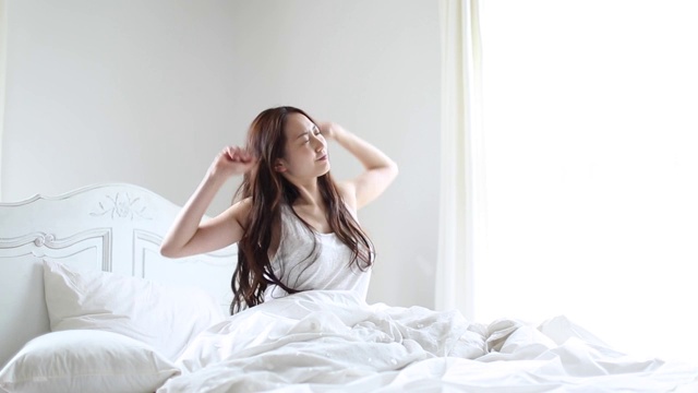 迷人的日本年轻女子在床上醒来视频素材