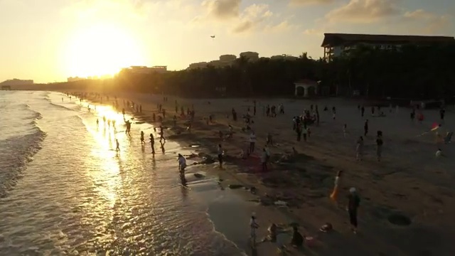 航拍文昌高隆湾夕阳下玩耍的人群视频素材