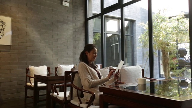 优雅的成熟女士在咖啡店使用平板电脑视频素材