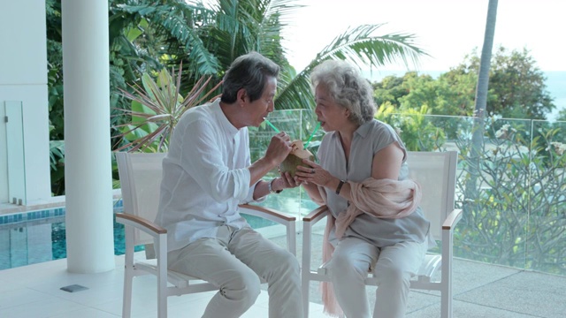 老年夫妇在露台喝椰汁视频素材
