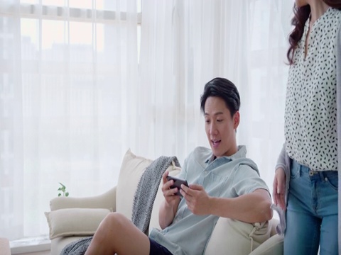 快乐的年轻情侣在客厅玩手机视频素材