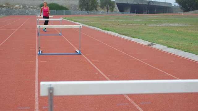 白人女运动员在4k体育场跑道上跑过栏视频下载