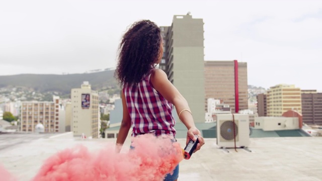 时尚的年轻女子在城市的屋顶上使用烟雾弹视频购买