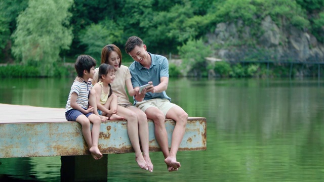 快乐的年轻家庭在户外使用手机视频素材