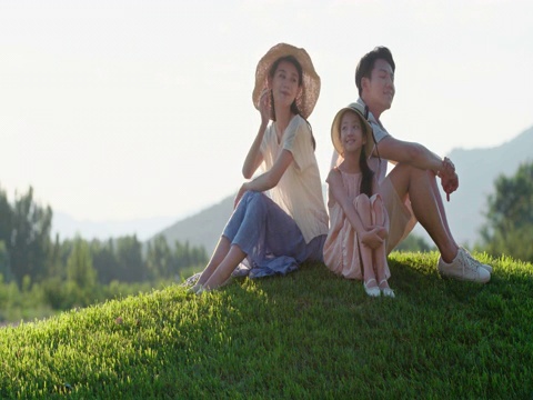 快乐的年轻家庭坐在草地上视频素材