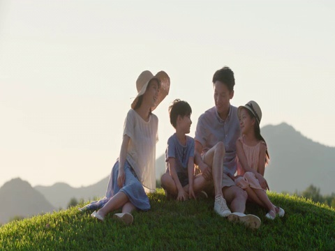 快乐的年轻家庭坐在草地上视频素材