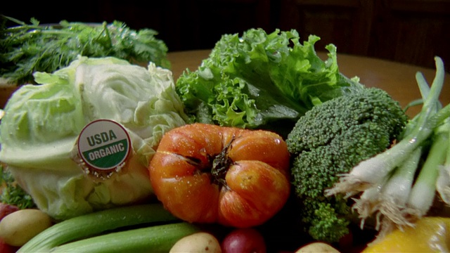 近距离地用平底锅盛着新鲜的有机蔬菜/拿起一个传家宝西红柿视频下载