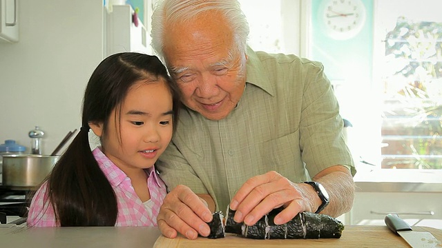 美国加州洛杉矶，祖父向孙女(8-9)演示如何切寿司卷视频下载