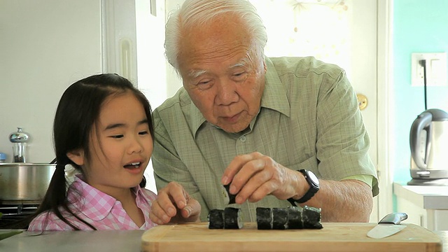 美国加州洛杉矶，爷爷向外孙女(8-9岁)演示如何切寿司卷视频下载