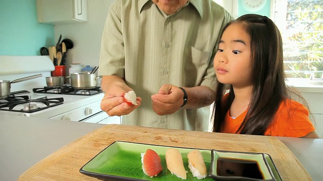 孙女(8-9岁)看着爷爷把最后一块寿司放到盘子里/美国加州洛杉矶视频下载