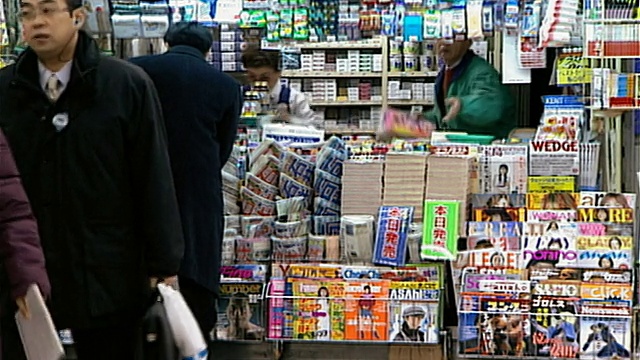 上下班高峰期，通勤者在新宿车站内的报摊上购买报纸/一名戴口罩的男子防止疾病传播/日本东京视频素材