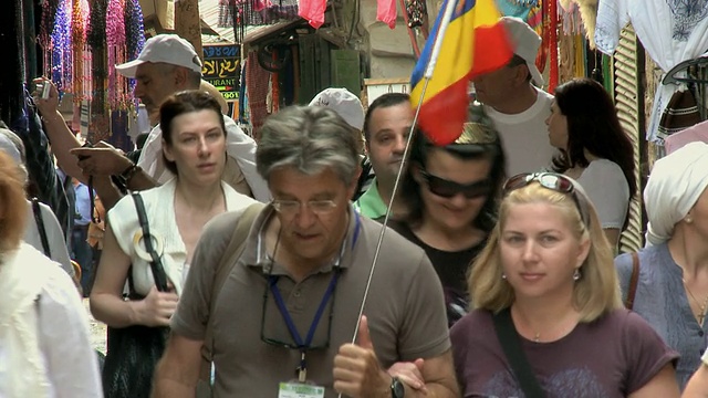 以色列耶路撒冷，游客举着罗马尼亚国旗穿过老城街道视频下载