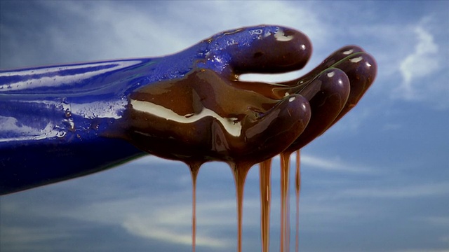 CU原油从戴着手套的手上滴下，背景是天空/亚特兰大，乔治亚州视频下载