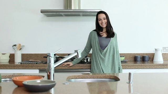 年轻女子在厨房做饭，对着镜头微笑视频下载