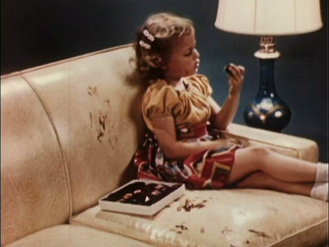 1956年MS女孩在皮沙发上吃盒装巧克力，沙发上布满了巧克力指纹/美国视频下载