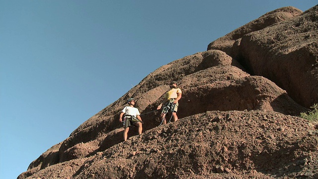 一个攀岩的人在其他攀岩者的帮助下举手击掌视频素材