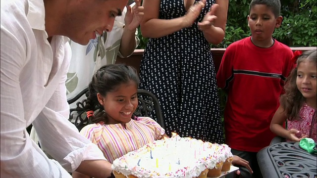 在家人为她鼓掌的时候，女孩吹灭了生日蛋糕上的蜡烛视频素材