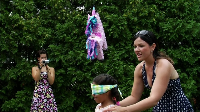 女人蒙着眼睛纺纱的女孩准备用棍子打皮纳塔/女人的背景拍摄与数码摄像机/新泽西视频素材