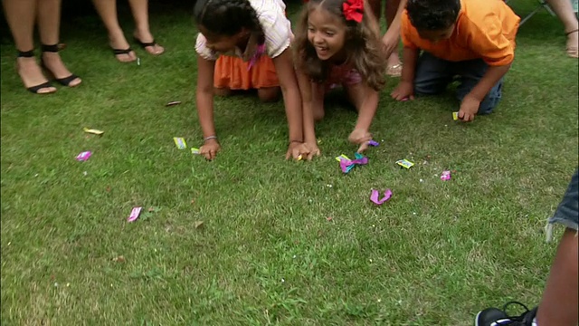 小男孩用木棍和糖果砸开彩罐/孩子们在草地上爬着抓糖果/新泽西视频素材