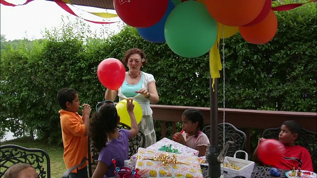 妇女和孩子们在儿童生日派对的甲板上吹气球/新泽西视频素材