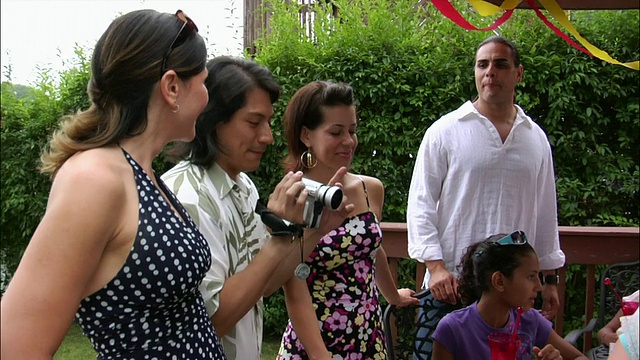 一名男子在生日派对上用数码摄像机拍摄家庭电影，人们在附近/新泽西观看视频素材