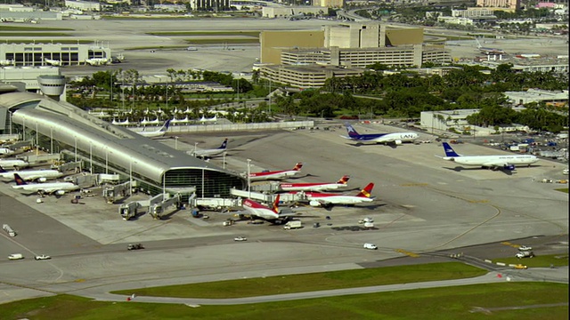 美国佛罗里达州迈阿密机场候机楼的全景，候机楼上停着飞机和过往车辆视频下载
