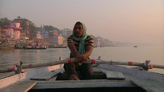 日落时分，印度北方邦瓦拉纳西，一名男子在小船上沿着恒河划船而下视频下载