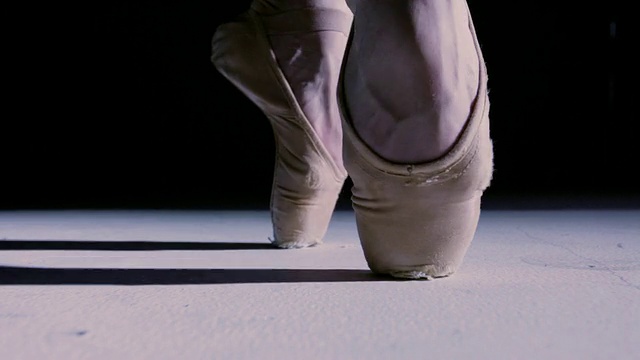 在聚光灯下，一名科罗拉多芭蕾舞女演员的脚在黑暗中穿梭，走向镜头/美国纽约视频素材