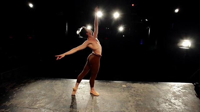 WS男芭蕾舞者在舞台上练习他的常规舞蹈，在舞台灯光下旋转/纽约，美国视频素材