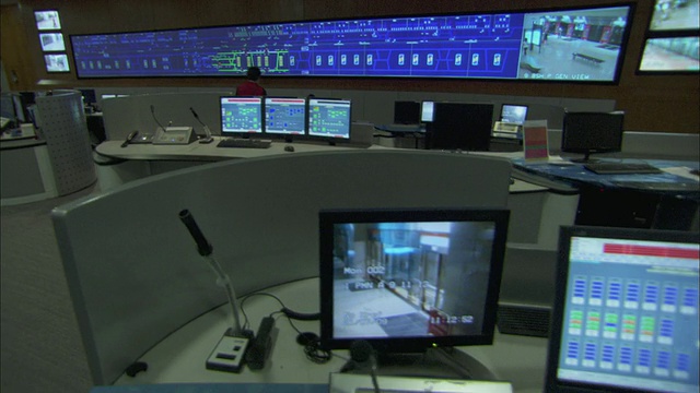 新加坡新加坡城，人们在工作站工作，在控制室的墙上安装了大型监控监视器视频下载