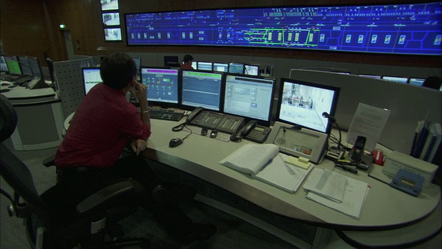 新加坡控制室墙上安装的大型监视监视器和工作站工作人员的照片视频下载