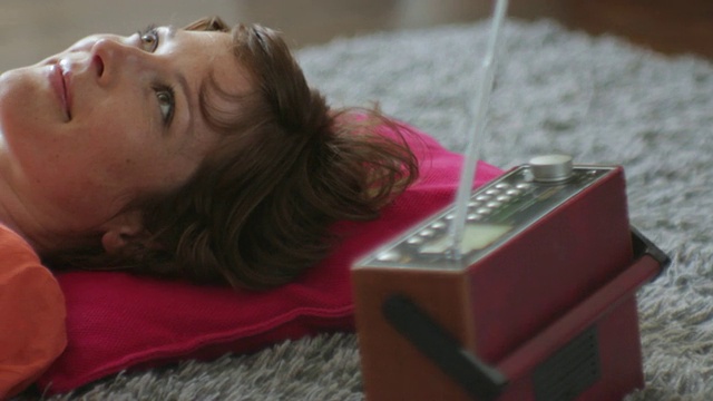 一名女子躺在地板上听广播，英国伦敦视频下载