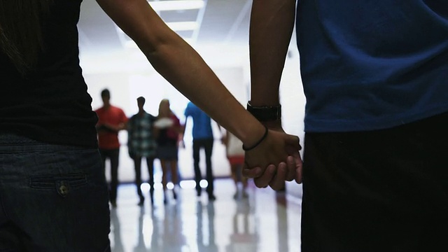 美国犹他州西班牙福克市的一对情侣手牵手走在学校走廊上视频素材