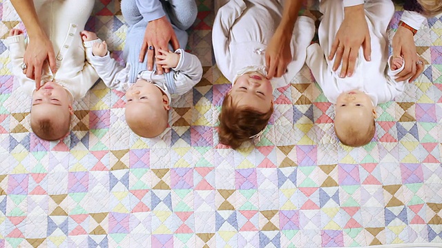 四个婴儿(6-11个月)躺在布上，妈妈的手/比利时布鲁塞尔视频素材