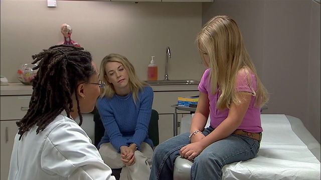 中等镜头的医生用听诊器听着女孩的心脏，母亲看着/在病历上做记录视频素材