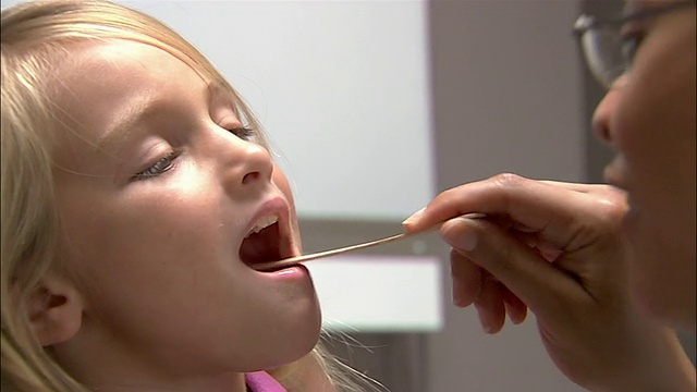 医生用压舌板检查小女孩的口腔和喉咙视频素材