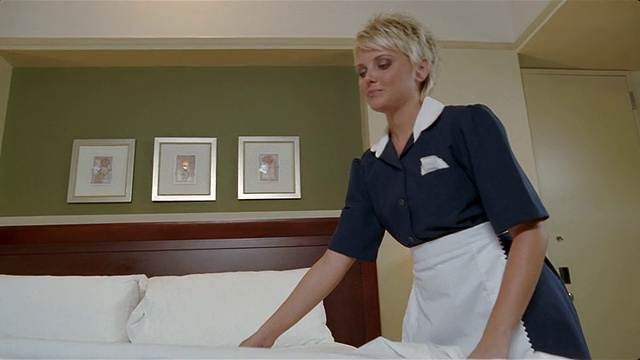 低角度中拍摄酒店客房服务员铺床视频素材