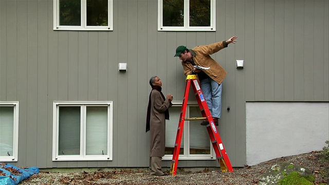 男人在梯子上测量房子二楼的窗户/房主走向男人/和男人聊天视频下载