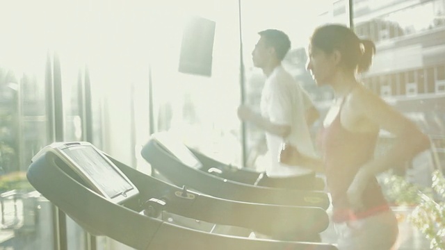 MS DS男人和女人在跑步机上跑步有氧运动在健身房/加拿大不列颠哥伦比亚省温哥华视频下载