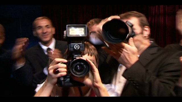 明星在红毯上的中景拍摄，粉丝们在挥手，狗仔队在拍照。/英国伦敦视频下载