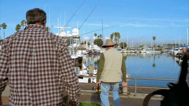 宽镜头的船在码头/汽车停车/男人走出和拥抱/拿起渔具，走向码头/长滩，加利福尼亚视频下载